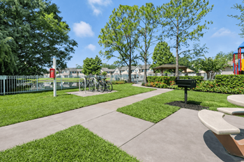 A park with a bench, a fence, and a tree.
